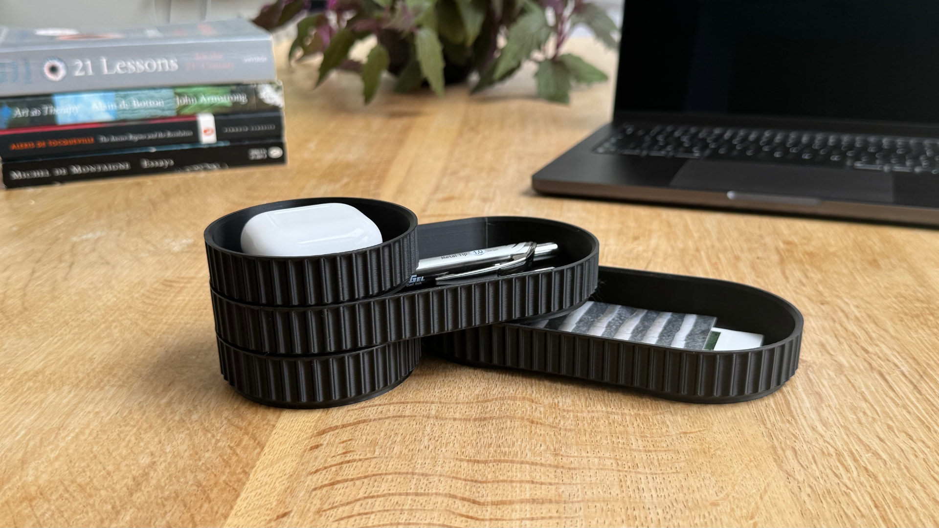 Modular desk organiser holding earbuds, pens and cards on a wooden desk
