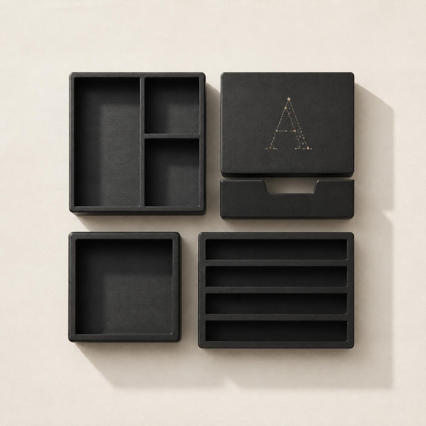 Top-down view of four charcoal black modular pieces, one marked with the initial A